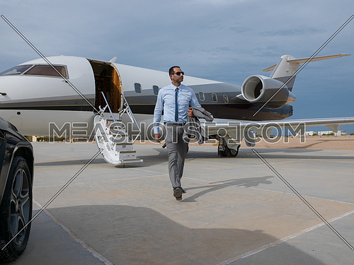 Portrait of a young successful middle eastern businessman at the airport in front of his private plane