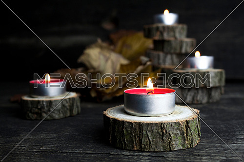 Christmas candles burning, decoration with wooden logs resting on rustic wooden background