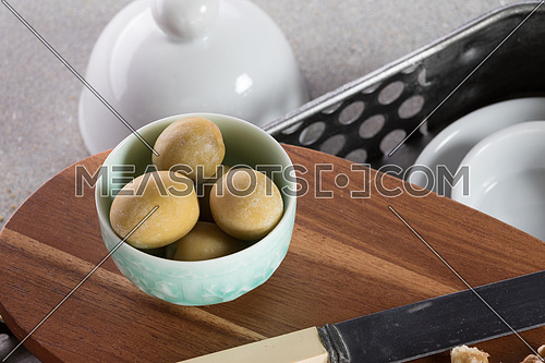 Green olives in a green bowl on a wooden tray