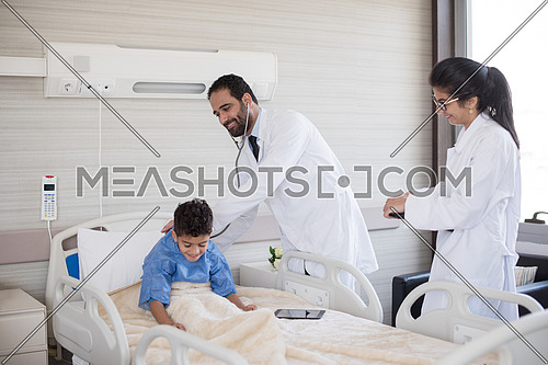 arabian mischievous and beauty kid get treatment by young doctors in modern hospital room