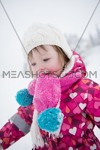 portrait of happy smiling little girl outdoors, having fun and playing on fresh snow on snowy  winter day