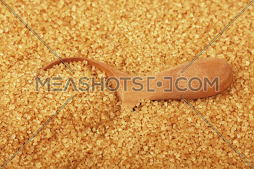 Close up one wooden scoop spoon in brown cane sugar, high angle view, selective focus