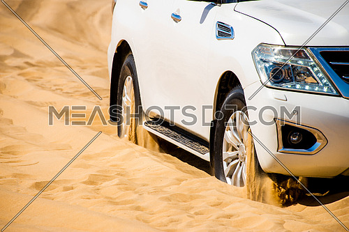 a white SUV stuck in the desert sand