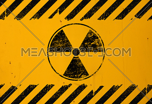 Black radioactive hazard warning sign painted over grunge yellow metal wall background with copy space