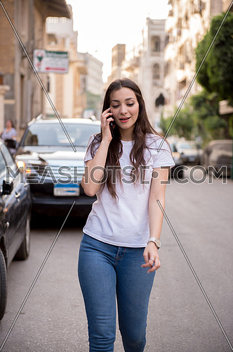 A young woman walking on the street talking in the mobile phone