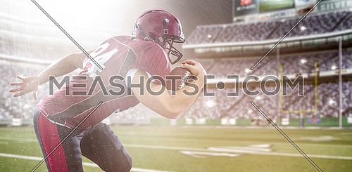 American football Player running with the ball isolated on big modern stadium field with lights and flares