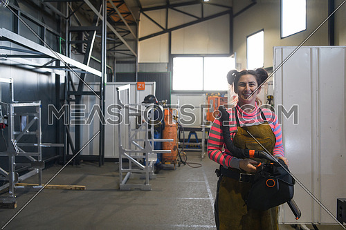 a portrait of a women welder holding a helmet and preparing for a working day in the metal industry. High quality photo