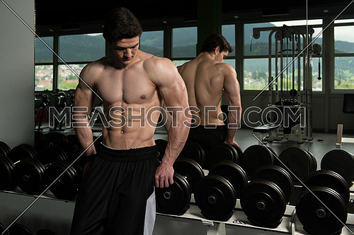 Young Man Standing Strong Next To The Mirror And Flexing Muscles - Muscular Athletic Bodybuilder Fitness Model Posing After Exercises
