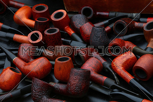 Close up many natural wooden tobacco smoking pipes on market stall, high angle view