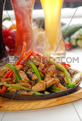 original fajita sizzling smoking hot served on iron plate ,with selection of beer and fresh vegetables on background ,MORE DELICIOUS FOOD ON PORTFOLIO