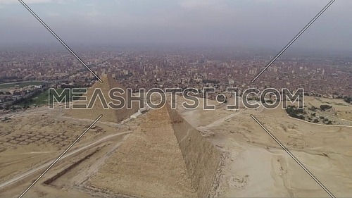 Reveal Shot for The Great Pyramid of Khufu (Cheops) and Pyramid of Menkaure at Great Pyramids of Giza Area in Cairo by day.