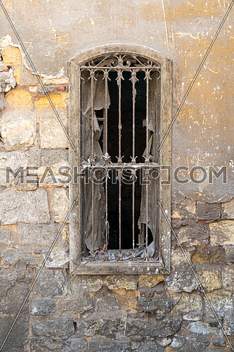 Old abandoned wall with one closed wooden window covered by broken wooden iron grid, Old Cairo, Egypt