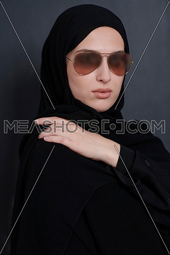 Young muslim businesswoman in traditional clothes or abaya and sunglasses posing in front of black chalkboard. Arab woman representing modern arabic lifestyle, islamic  fashion and Ramadan kareem concept
