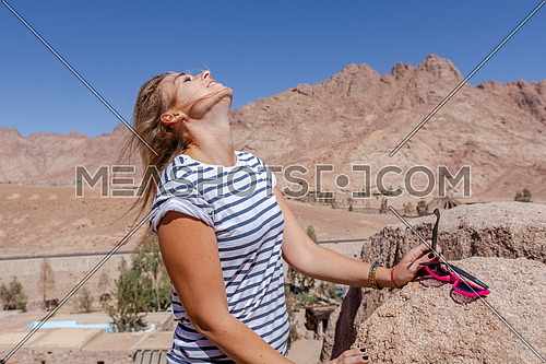 mid-shot for a female tourist spreading her hair while exploring Sinai Mountain for wadi Freij at day.