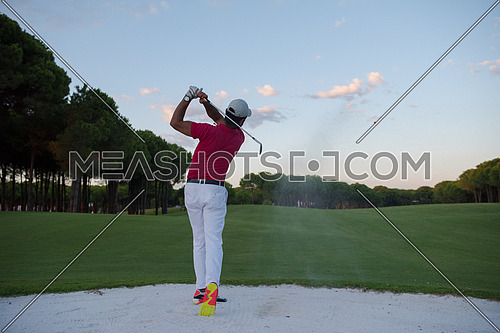 golf player shot ball from sand bunker at course with beautiful sunset with sun flare