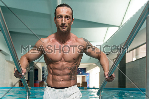 Happy Attractive Muscular Mature Man Resting Relaxed On Edge Of Swimming Pool