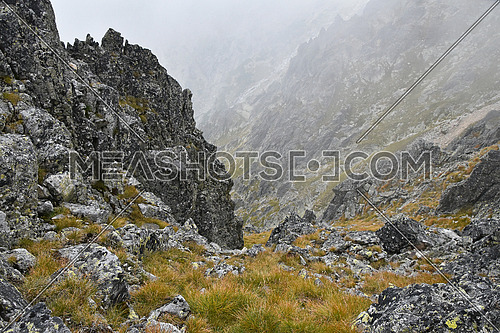 Landscape of dark rocky mountain ridge in foggy clouds, High Tatra mountains