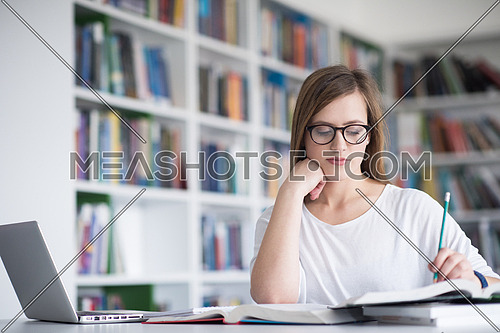 female student study in school library, using laptop and searching for informations on internet