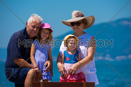 portrait of  happy grandparents with cute little granddaughters having fun on a bench by the sea during Summer vacation  Healthy family holiday concept