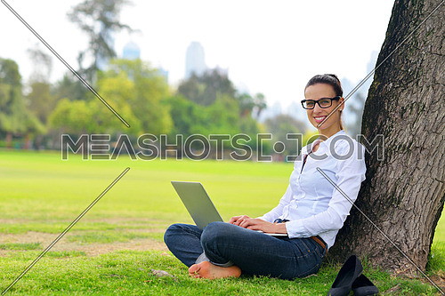 happy young student woman with laptop in city park study