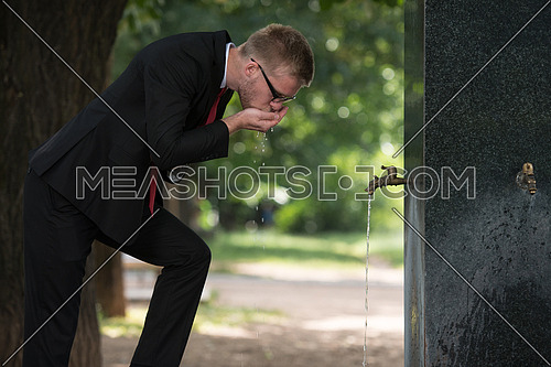 Young Businessman Refreshing Himself By Drinking Water