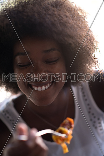young beautiful African American woman enjoys while eating delicious pasta