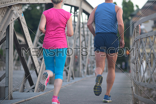 healthy mature couple jogging in the city  at early morning with sunrise in background