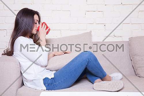A girl sitting on a couch drinking coffee
