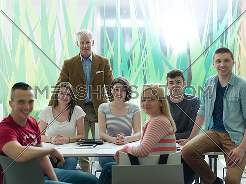 portrait of confident teacher in school classroom,  students group on class in background