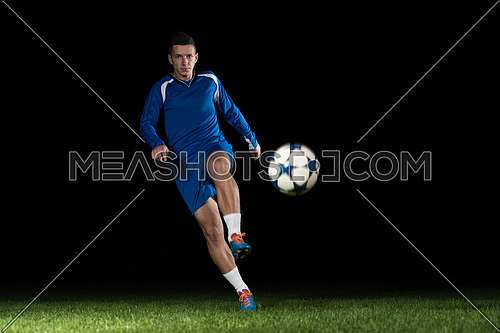 Soccer Player Doing Kick With Ball On Football Stadium Field Isolated On Black Background