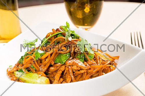 classic fresh chinese fried noodles with pork and vegetables and coriander on top