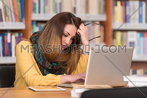 Stressed Student Of High School Sitting At The Library Desk - Shallow Depth Of Field
