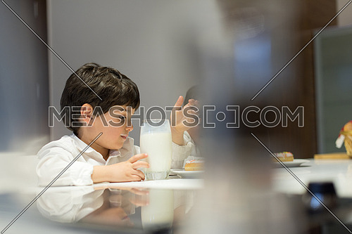 little middle east boy in the kitchen eating a snack and drinks milk with pleasurelittle middle east boy and girl eating snacks and drinking milk in the kitchen with pleasure