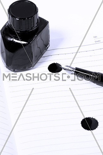 classic black fountain pen on open notebook with ink bottle with stain on page,blue filter