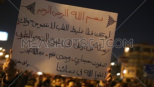 Protesters holding signs at near the presidential palace against Morsi's constitutional declaration at night - December 2012