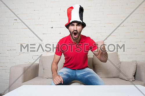 young man watching football game wearing Egyptian flag hat