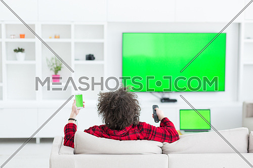 young handsome man in bathrobe enjoying free time watching television in his luxury home