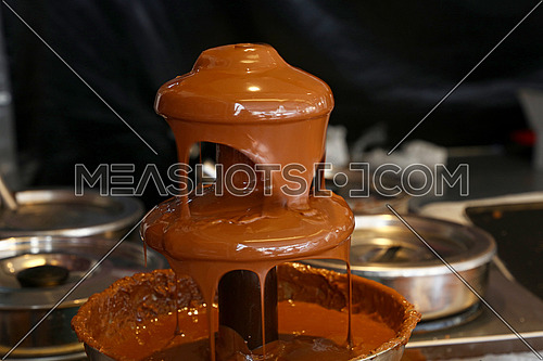 Close up of Belgian liquid milk chocolate fountain for sweet fondue dip desserts, low angle view