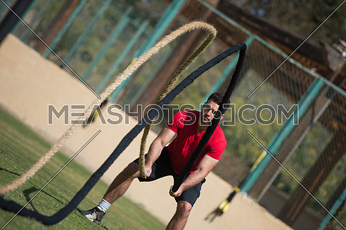 young middle eastern athletic man hard workout battle ropes outside on a sunny day