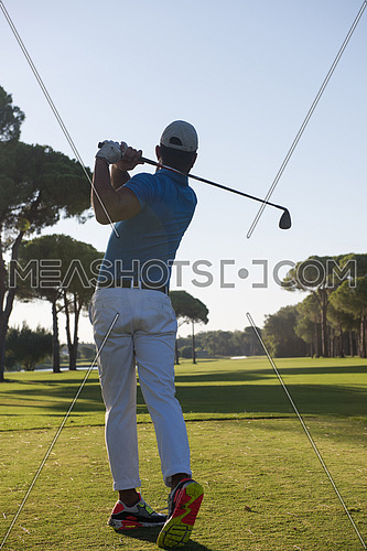 golf player hitting shot with club on course at beautiful morning with sun flare in background