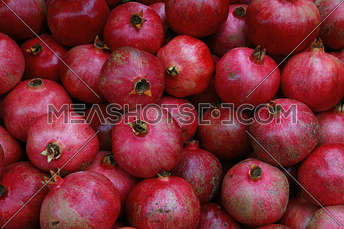 Fresh red ripe pomegranates at retail market stall display, close up, elevated high angle view