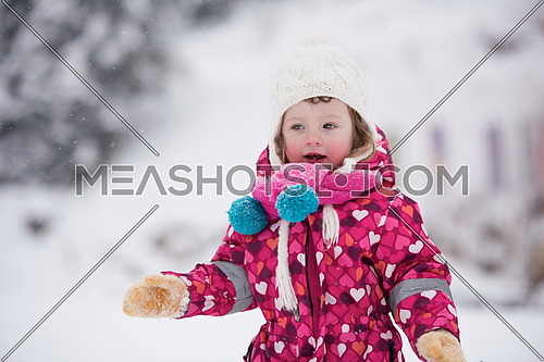 portrait of happy smiling little girl outdoors, having fun and playing on fresh snow on snowy  winter day