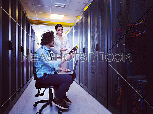 Team of young technicians working together on servers at the data center using laptop computer