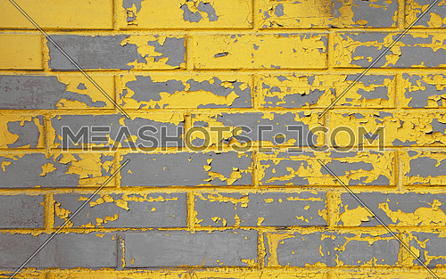 Old grunge weathered gray concrete brick wall with scaling yellow paint flakes, stains and defects