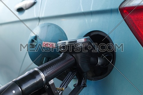 Refueling the car at a gas station fuel pump, open cap of a fuel tank of a vehicle with red sign for Diesel
