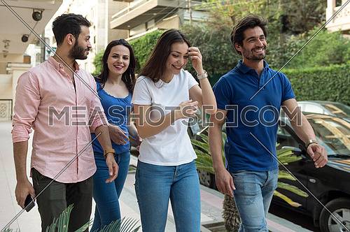 A group of young people speak and laugh as they walk in the street