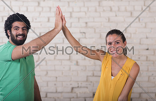 two young middle eastern informal businessman celebrating success with high five to each other in creative office