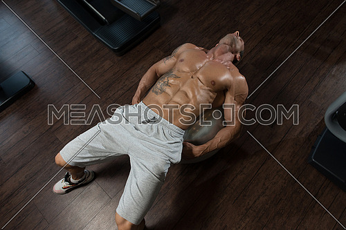 Muscular Mature Man Exercising Abdominals On Exercise Ball In Modern Fitness Center