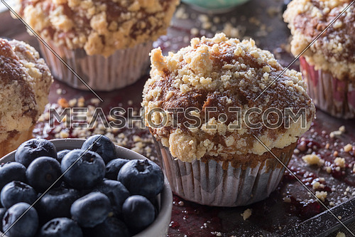 Muffins with crumbs and blueberry in a white bowl on a tray moist with jam