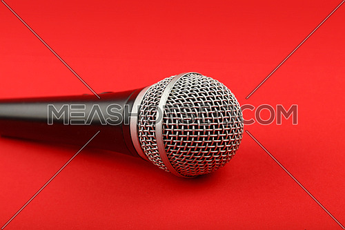 Black and silver vocal microphone side view close up on red background